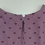 Close-up of pink checkered dress with small dark heart patterns and a zipper at the back for a stylish look.
