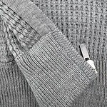 Close-up of a gray knit sweater featuring textured patterns and a silver zipper detail, showcasing cozy winter fashion for men and women.