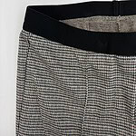 Close-up of stylish checkered women's trousers with black waistband, suitable for office or casual wear, showcasing modern fashion trends.