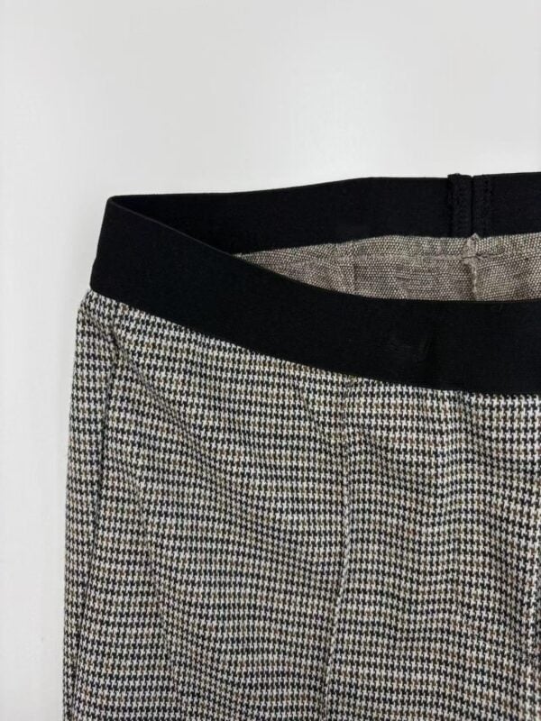Close-up of stylish checkered women's trousers with black waistband, suitable for office or casual wear, showcasing modern fashion trends.