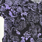 Close-up of a black dress with purple floral and paisley patterns, featuring an elastic waistband and intricate design details.