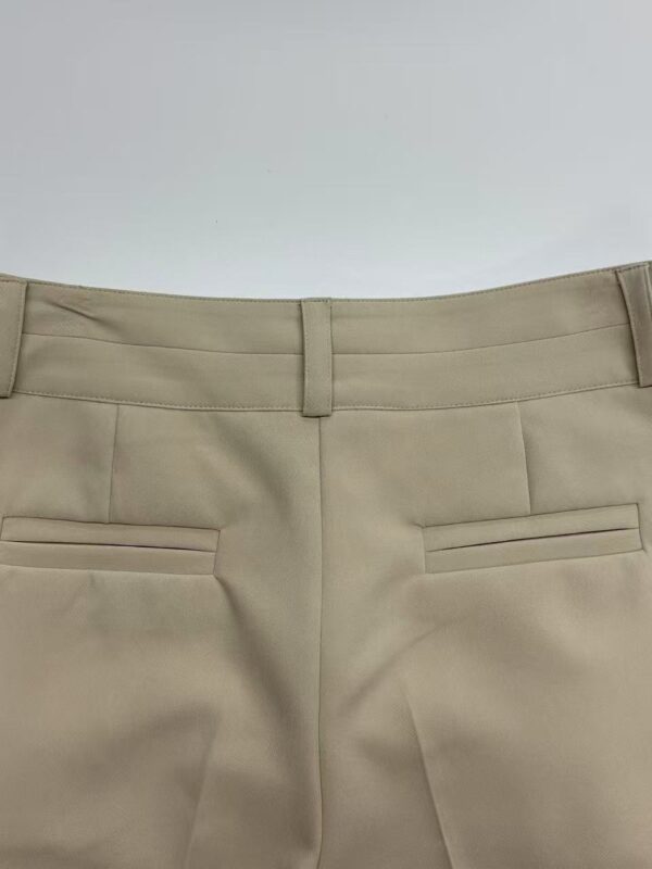 Close-up of beige women's dress pants with tailored fit and sleek design, perfect for professional or formal occasions.