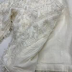 Close-up of luxurious ivory lace and silk fabric, showcasing intricate embroidery and delicate texture, ideal for high-end fashion or bridal wear.