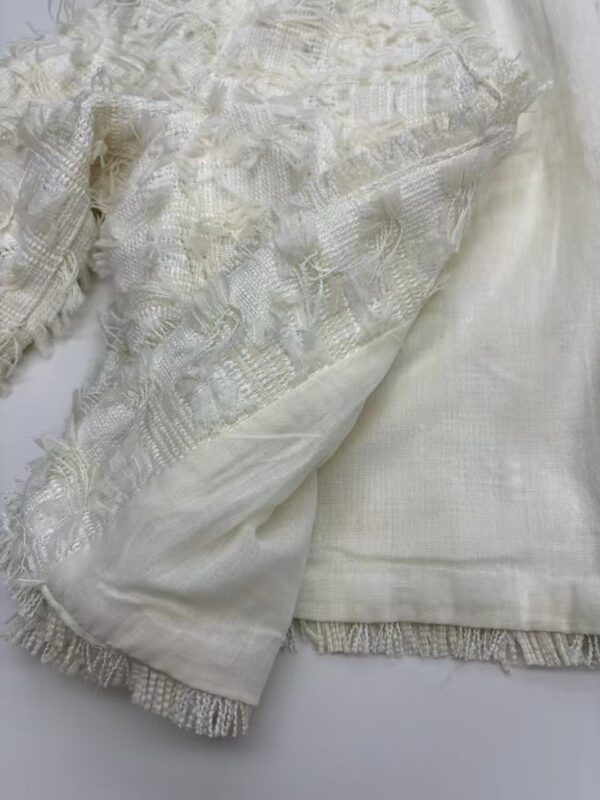 Close-up of luxurious ivory lace and silk fabric, showcasing intricate embroidery and delicate texture, ideal for high-end fashion or bridal wear.