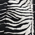Close-up of black and white zebra print fabric, showcasing bold stripes suitable for stylish clothing and accessories.