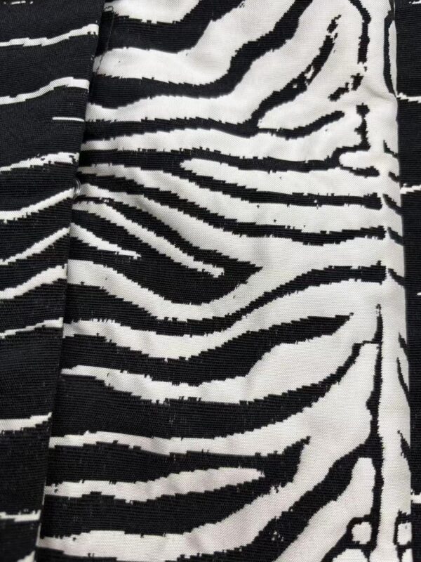 Close-up of black and white zebra print fabric, showcasing bold stripes suitable for stylish clothing and accessories.