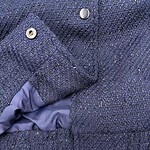 Close-up of a navy blue tweed women's jacket with detailed fabric texture and metallic buttons, showcasing stylish and high-quality fashion.