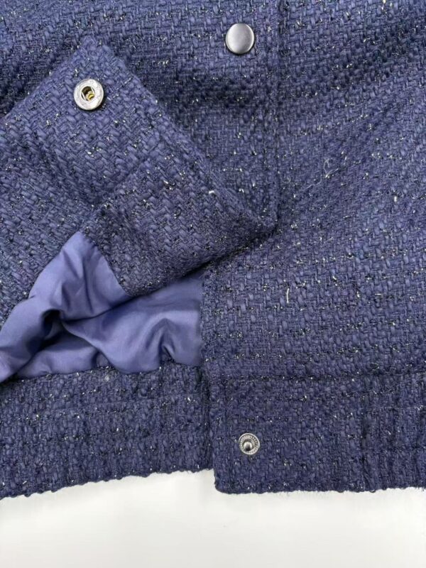 Close-up of a navy blue tweed women's jacket with detailed fabric texture and metallic buttons, showcasing stylish and high-quality fashion.
