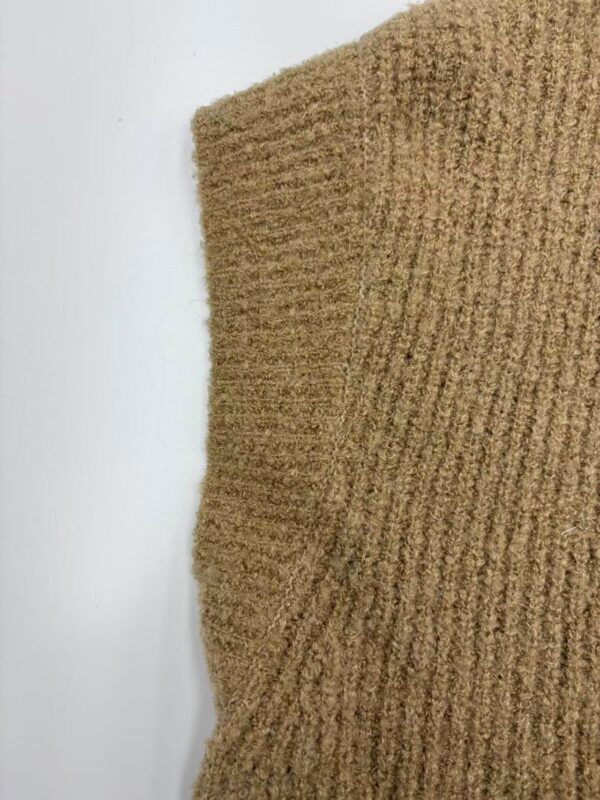 Close-up of a brown knitted sweater showcasing textured fabric and ribbed pattern, perfect for autumn and winter wear.