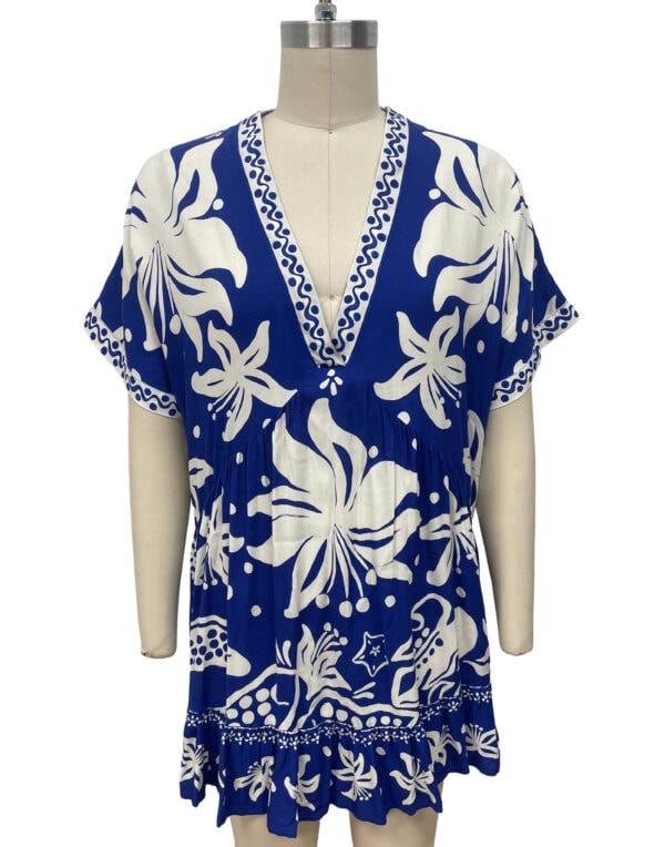 Stylish blue and white floral beach cover-up with a V-neckline, short sleeves, and ruffled hem, perfect for summer beachwear and resort fashion.