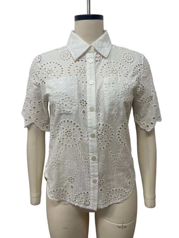 White eyelet blouse with intricate cut-out patterns, short sleeves, and a classic collar, perfect for casual or semi-formal occasions.