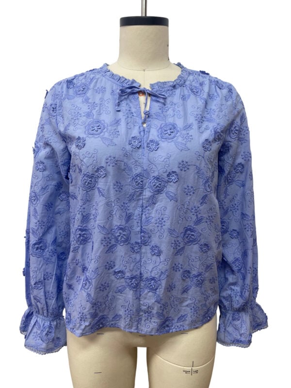 Light blue floral blouse with ruffled cuffs and tie-neck detail, perfect for casual or semi-formal wear.