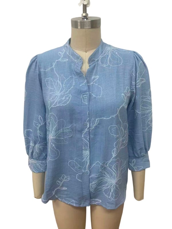 Light blue women's blouse with white floral embroidery, button-up front, and three-quarter sleeves, perfect for casual or semi-formal wear.