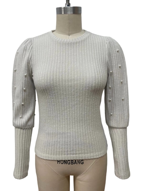 Cream-colored ribbed sweater with pearl embellishments on the shoulders and sleeves, featuring a fitted design and round neckline, perfect for stylish winter wear.