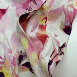 Close-up of floral fabric with pink, yellow, and purple hues, suitable for fashion and clothing design.