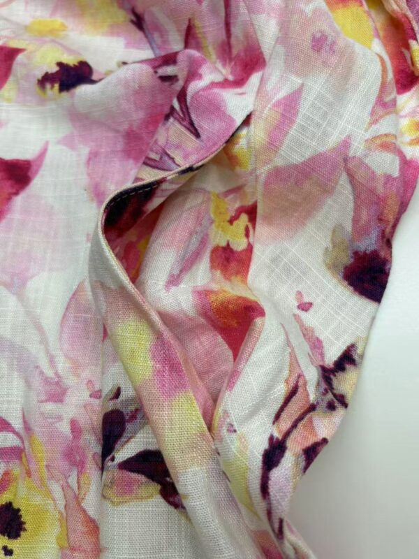 Close-up of floral fabric with pink, yellow, and purple hues, suitable for fashion and clothing design.