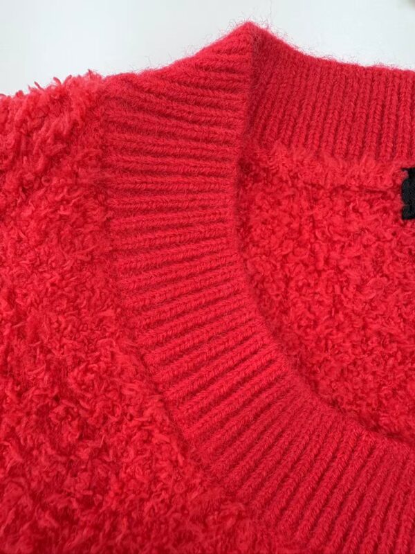 Close-up of a vibrant red knit sweater with textured fabric and ribbed collar, perfect for fall and winter fashion.