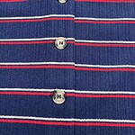 Close-up of a blue knitted cardigan with red and white horizontal stripes and four buttons down the front.