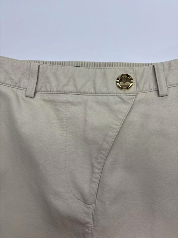 Close-up of beige casual men's pants with a metal button and belt loops, suitable for everyday wear and fashion.