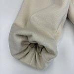 Close-up of a cream-colored fabric sleeve with gathered elastic cuff, showcasing soft texture and elegant design for fashion and clothing.