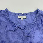 Close-up of a blue embroidered blouse with ruffled neckline and tie detail, perfect for stylish casual or semi-formal wear.