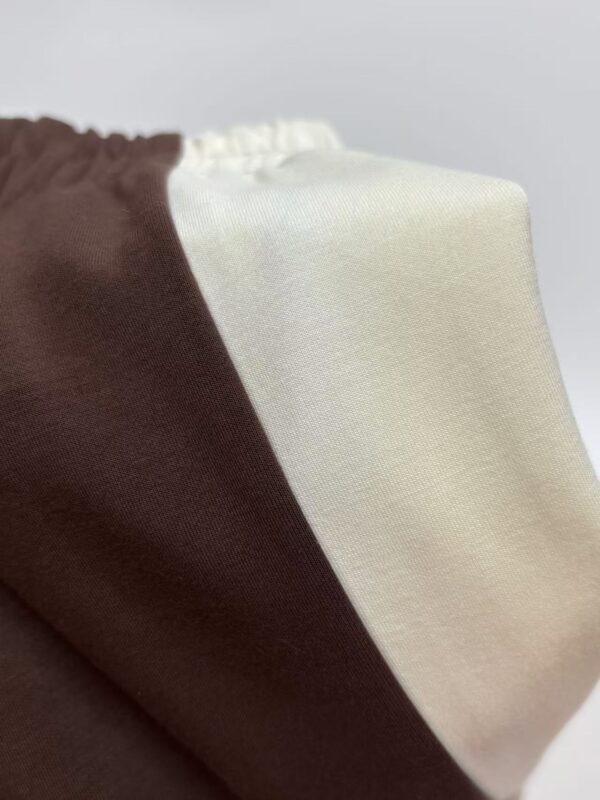Close-up of fabric with brown and cream color blocks, showcasing smooth texture and clean lines, ideal for fashion and apparel design.