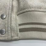 Close-up of a luxury grey wool coat featuring ribbed cuffs and metallic buttons, perfect for stylish winter wear.