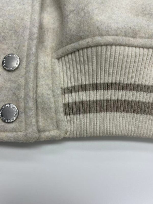 Close-up of a luxury grey wool coat featuring ribbed cuffs and metallic buttons, perfect for stylish winter wear.