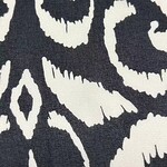 Close-up of a black and white patterned fabric with intricate swirling and geometric designs, ideal for fashion and home decor.