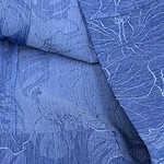 Close-up of blue textured fabric with intricate patterns, ideal for fashion design and clothing accessories.