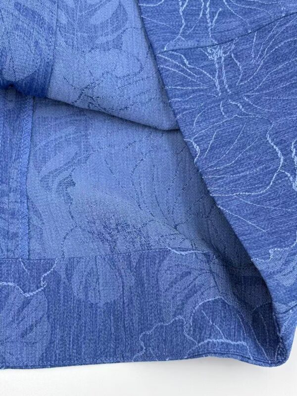 Close-up of blue textured fabric with intricate patterns, ideal for fashion design and clothing accessories.