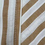 Close-up of striped fabric with white and beige tones, showcasing detailed weaving and texture, ideal for fashion and textile design.