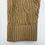 Close-up of a cozy, beige cable knit sweater with intricate patterns and ribbed cuffs, perfect for autumn and winter wear.