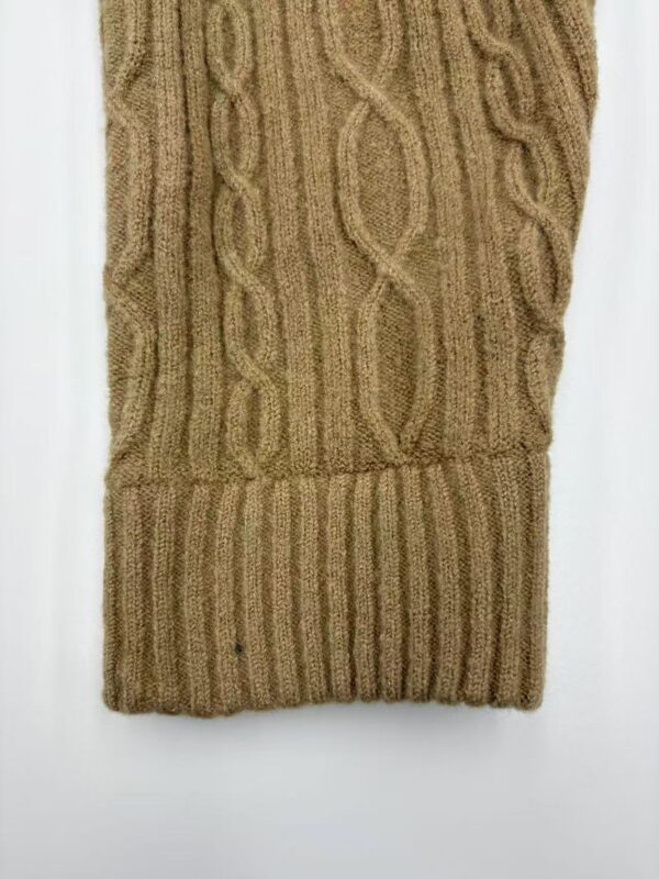 Close-up of a cozy, beige cable knit sweater with intricate patterns and ribbed cuffs, perfect for autumn and winter wear.