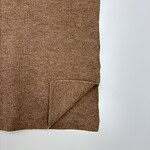 Close-up of a brown ribbed sweater fabric with a folded corner, showcasing its texture and warm tone.
