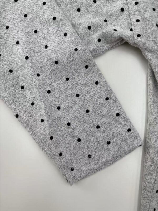 Close-up of a gray women's sweater with black polka dots, showcasing soft fabric and stylish design, ideal for casual or office wear.