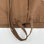 Close-up of brown fabric with white embroidered floral pattern and tied fabric straps, suitable for fashion or textile product SEO.