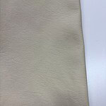 Close-up of beige leather fabric showing fine texture and subtle grain details, ideal for fashion and upholstery applications.