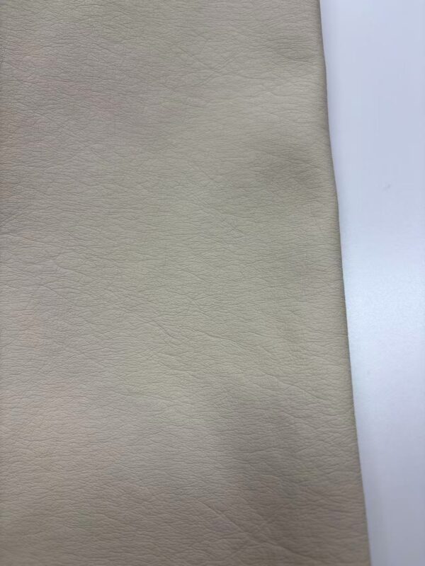 Close-up of beige leather fabric showing fine texture and subtle grain details, ideal for fashion and upholstery applications.