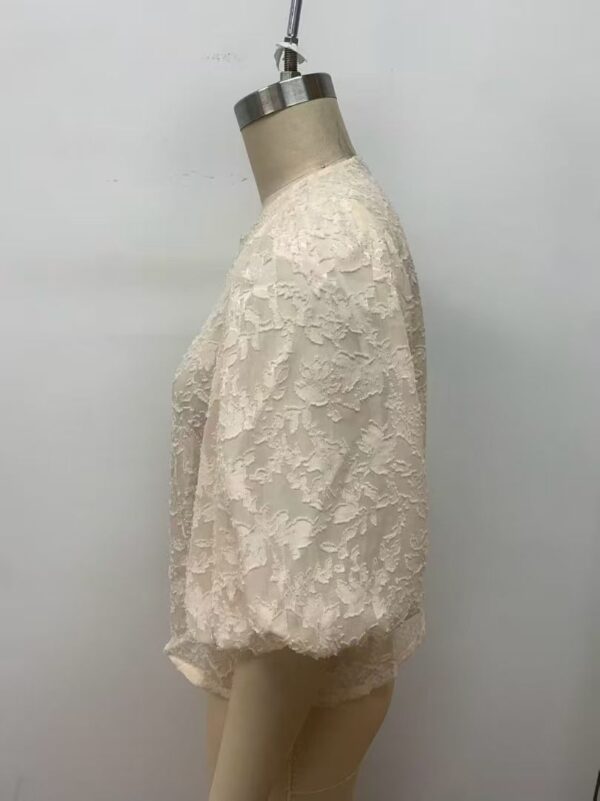 Cream-colored lace wedding top displayed on a mannequin, featuring intricate floral embroidery and a classic round neckline.