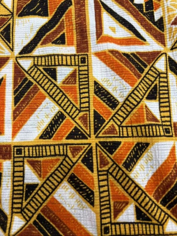 Close-up of vibrant African-inspired fabric with geometric patterns in black, orange, yellow, and white colors, featuring rulers as part of the design.