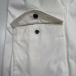 Close-up of a white fabric pocket with a button closure, showcasing fine stitching and clean design, ideal for fashion and clothing product images.