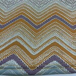 Vibrant zigzag beaded textile with multicolored patterns including green, purple, gold, and silver beads, showcasing intricate craftsmanship and detailed beadwork.