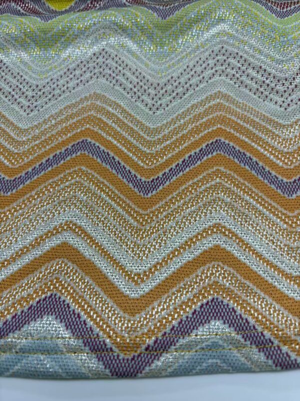 Vibrant zigzag beaded textile with multicolored patterns including green, purple, gold, and silver beads, showcasing intricate craftsmanship and detailed beadwork.
