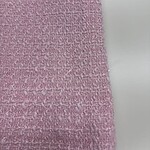 Close-up of pink textured fabric with a rough, woven surface, ideal for fashion and textile projects.
