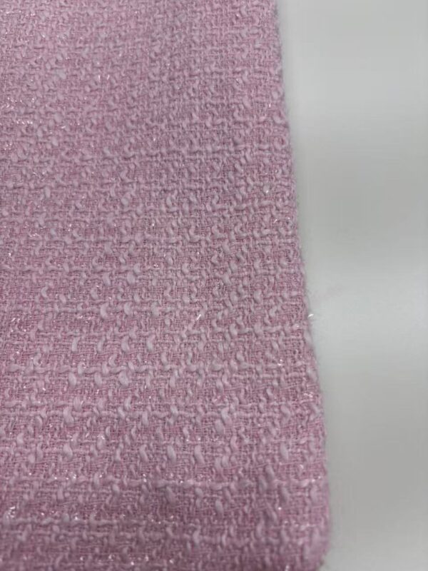 Close-up of pink textured fabric with a rough, woven surface, ideal for fashion and textile projects.