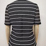 Close-up of a black and white striped knit sweater displayed on a mannequin, showcasing the textured fabric and pattern.