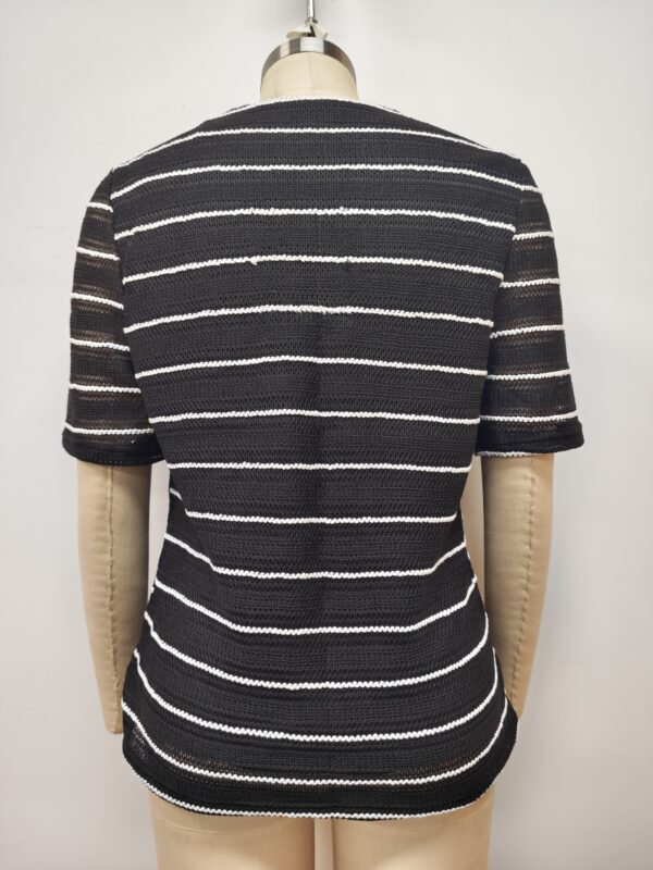 Close-up of a black and white striped knit sweater displayed on a mannequin, showcasing the textured fabric and pattern.