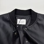 Close-up of a black leather bomber jacket with snap buttons and ribbed collar, perfect for casual and streetwear fashion.