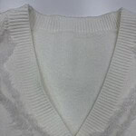 Close-up of a white knit cardigan with a V-neck and a single button, showcasing detailed knitting and soft fabric suitable for stylish casual wear.